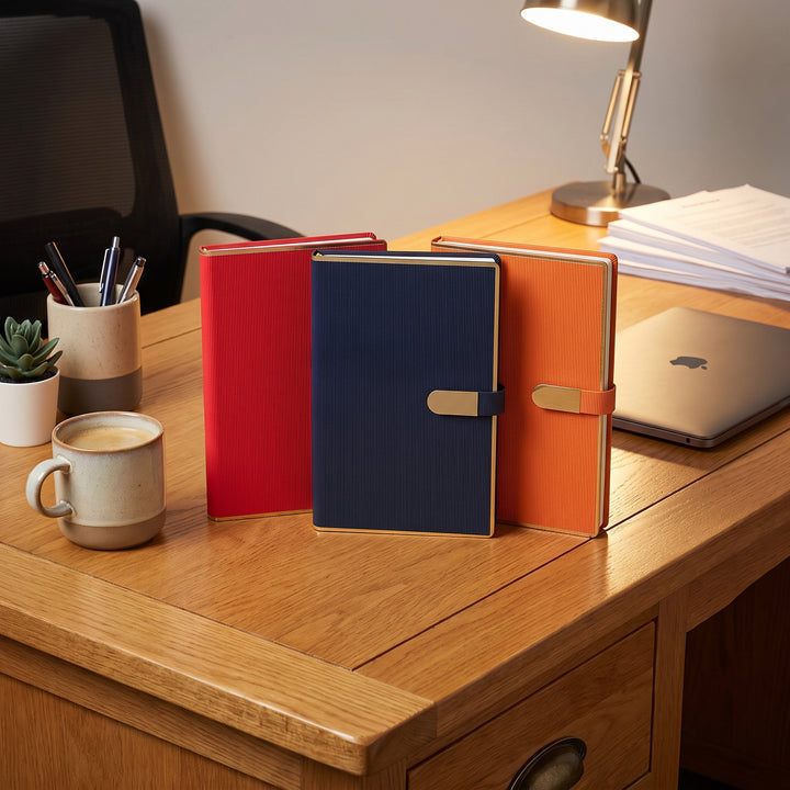 Custom branded A5 fine-ribbed leatherette notebooks with gold border trim in Nairobi