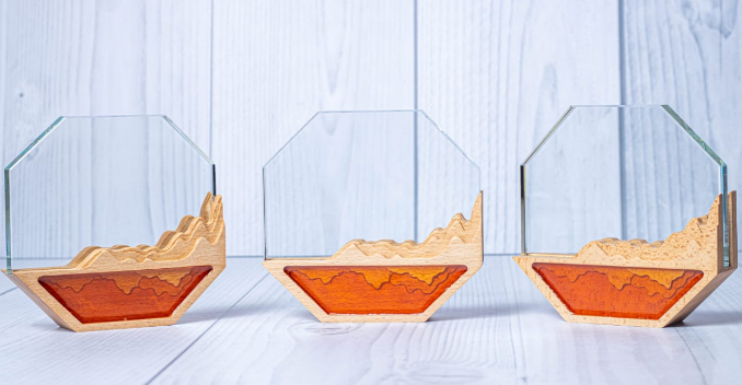Custom laser-engraved octagonal glass award with layered wood mountain base by Print365 Kenya