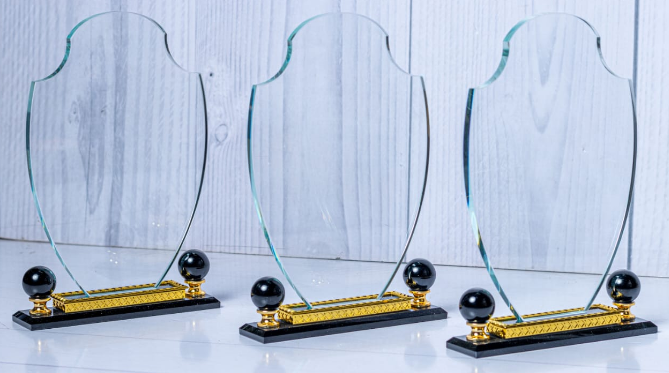 Custom laser-engraved shield-shaped crystal award trophy with black base and gold accents by Print365 Kenya