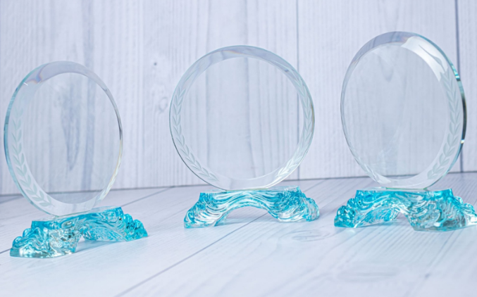 Custom laser-engraved circular crystal award trophy with aqua blue wave base by Print365 Kenya