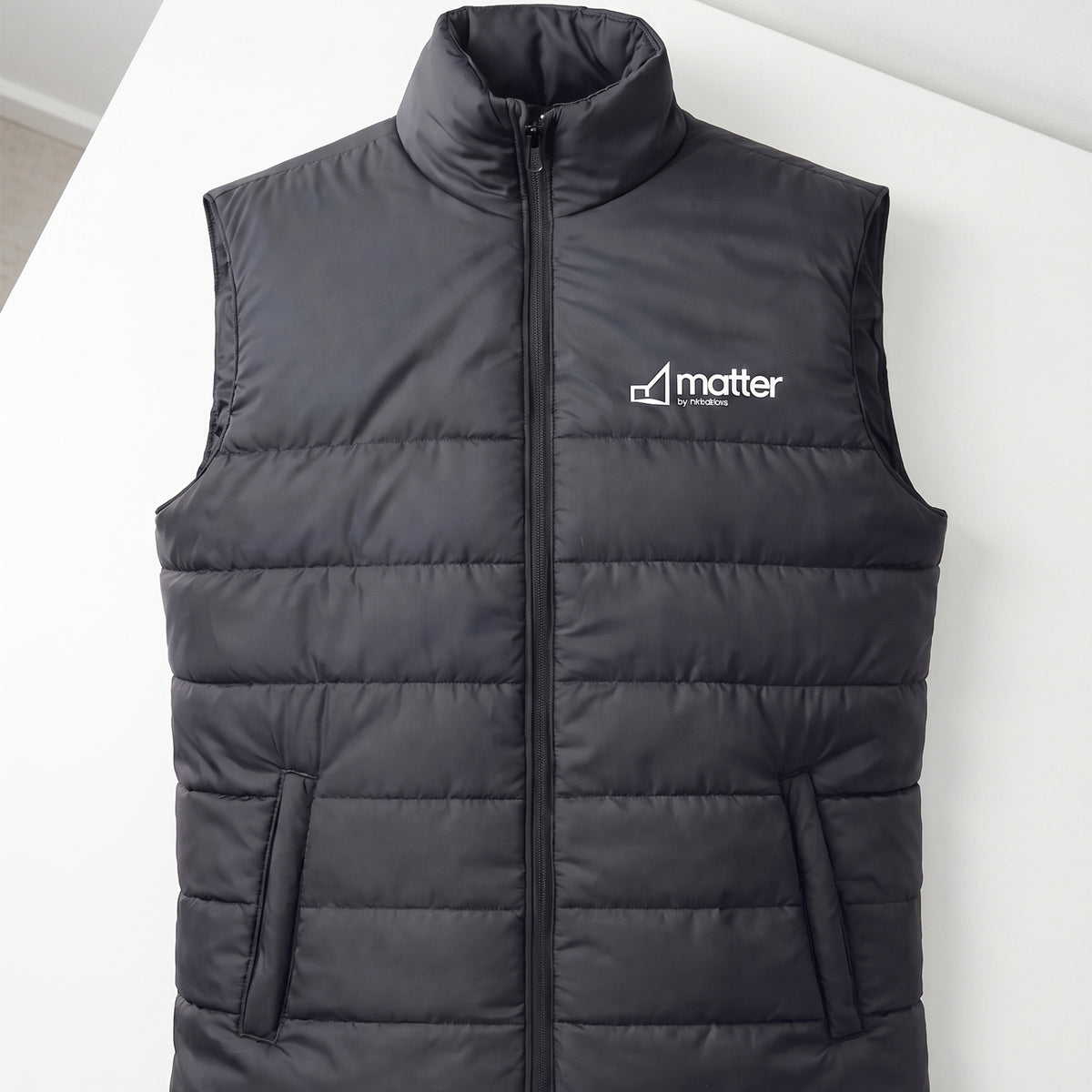 Custom black quilted puffer vest with a stand-up collar and front zipper done in Nairobi, Kenya