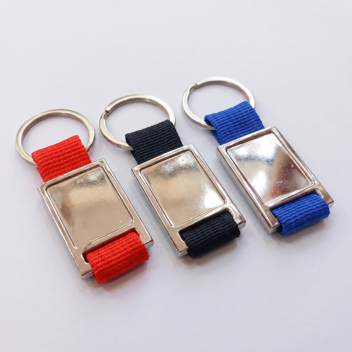Custom laser-engraved metal and woven fabric strap keyholder in red, black, and blue by Print365 Kenya