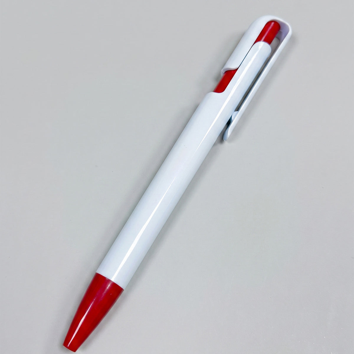 Promotional white plastic ballpoint pen featuring vibrant red grip and clip accents by Print365 Nairobi