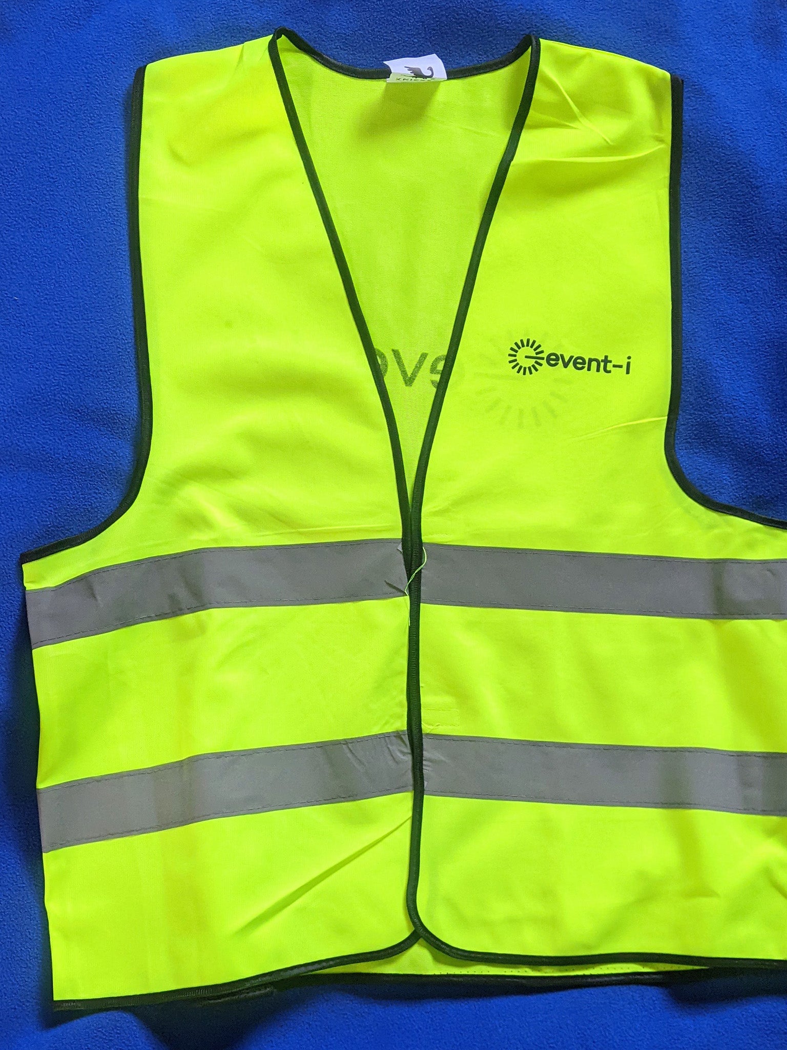Green safety vest with reflective stripes on a blue background