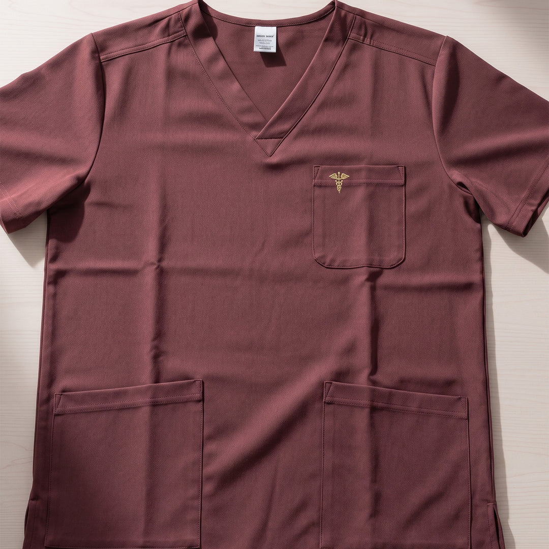 Personalized short-sleeve V-neck medical scrub top in a dusty rose or mauve color. It features a chest pocket with a small gold caduceus symbol and two large front utility pockets done in Nairobi, Kenya