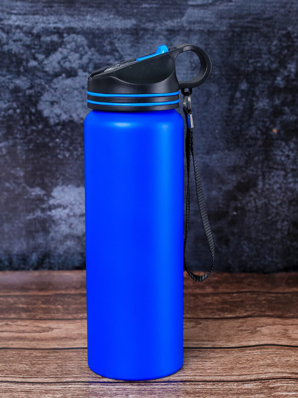 A custom, metal, matte blue insulated water bottle with a black lid and carrying loop by Print365 Kenya
